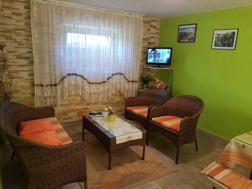 a living room with chairs and a table and a television at Apartment Tomašević in Slunj