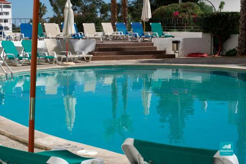 a swimming pool with blue chairs and a swimming poolvisor at Mirachoro Albufeira in Albufeira