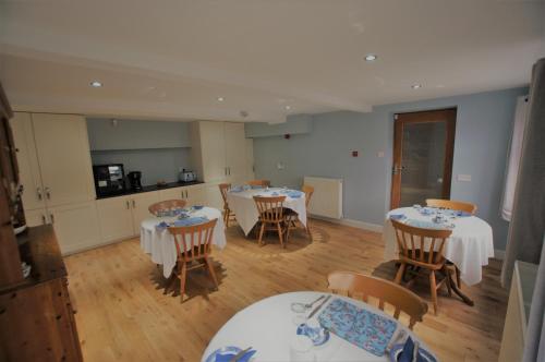 a dining room with tables and chairs and a kitchen at Dove House in Cheltenham