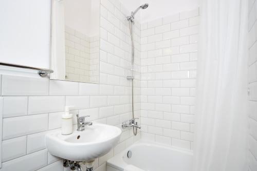 a white bathroom with a sink and a tub at Royal Route Place for You in Warsaw