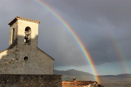 a rainbow over a church with a tower at La Fontaine in Bargème