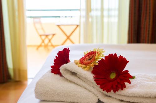 una pila de toallas con flores en una cama en Mirachoro Carvoeiro, en Carvoeiro