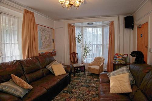een woonkamer met een leren bank en een stoel bij Ivy House B&B in Dolgellau