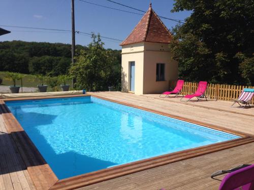een zwembad met twee roze stoelen naast een huis bij La Grange in Le Vigan