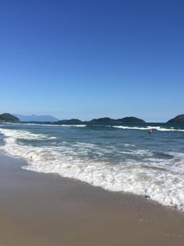 a beach with the ocean and a person in the water at Pousada Tô na Praia Juquehy in Juquei