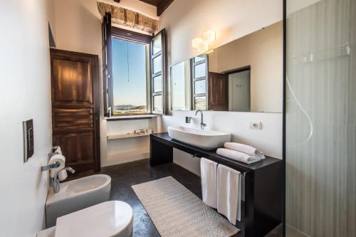 uma casa de banho com um lavatório, um WC e um espelho. em Faro Capo Spartivento em Chia