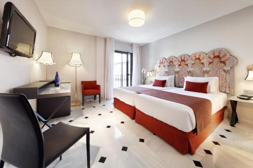 a bedroom with a bed and a desk and a tv at Eurostars Conquistador in Córdoba