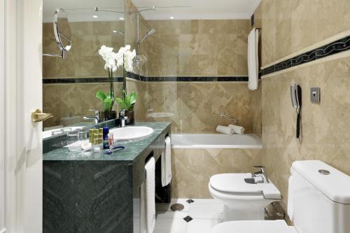 a bathroom with a toilet and a sink and a tub at Eurostars Conquistador in Córdoba