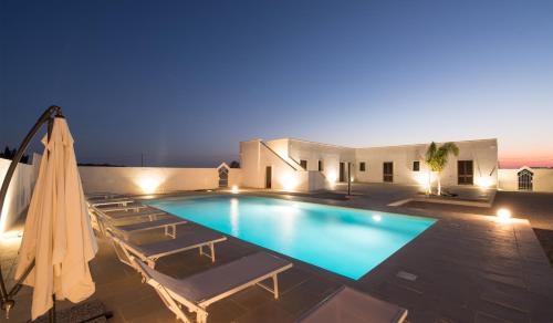 a swimming pool with chairs and an umbrella at Villa Lupia in Cutrofiano