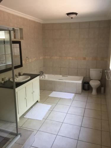 a bathroom with a tub and a toilet and a sink at Summerview Guest Lodge in Johannesburg