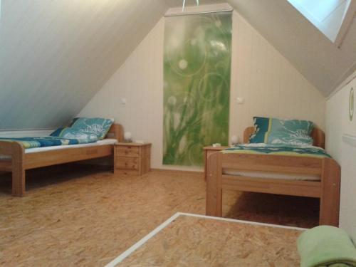 Cette chambre mansardée comprend 2 lits et un tableau mural. dans l'établissement Ferienwohnung Sandhoege, à Börger