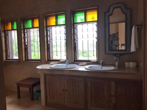 a bathroom with two sinks and a mirror and windows at Villa Volandrella - in front of Watamu Beach in Watamu