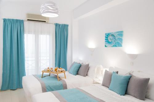 a living room with two white beds and blue curtains at Kafieris View in Firostefani