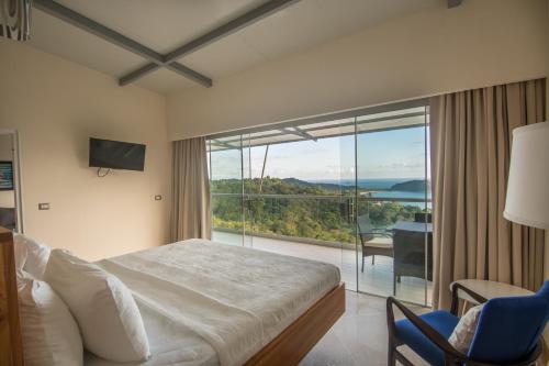 マヌエル・アントニオにあるLa Mariposa Apartmentsのベッドと大きな窓が備わるホテルルームです。