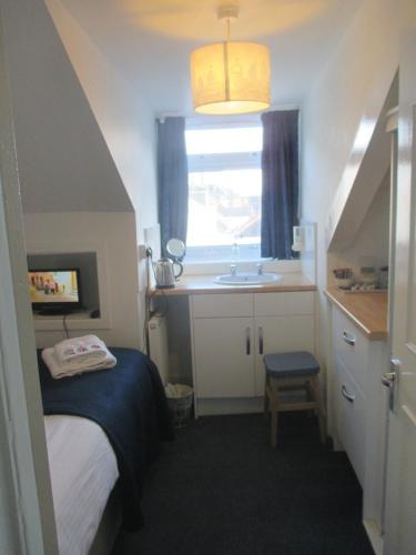 a small bedroom with a bed and a sink at Caledonia Guest House in Plymouth