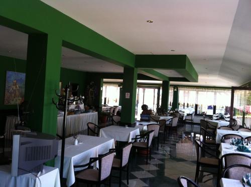 a restaurant with white tables and chairs and green walls at Guesthouse Palombaro in Umag