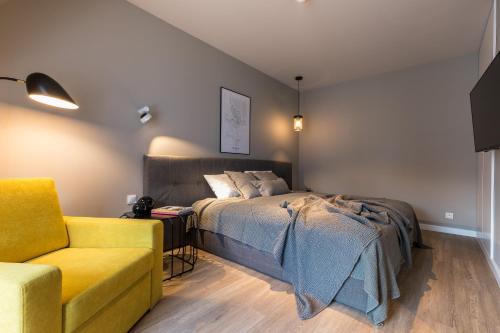 a bedroom with a bed and a yellow chair at Tartaczna Street Apartment in Gdańsk