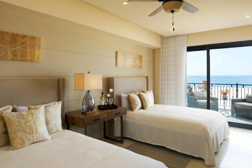 a hotel room with two beds and a balcony at Grand Solmar Pacific Dunes Resort, Golf & Spa in Cabo San Lucas