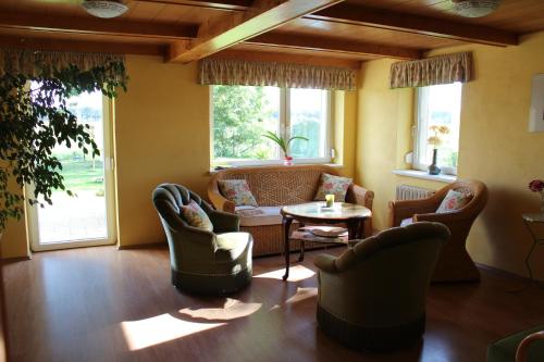 a living room with chairs and a table and windows at Ferienhaus Loose 8 in Letschin
