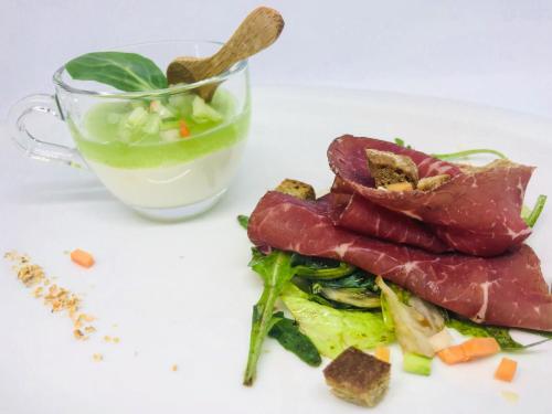 a plate of food with meat and a cup of drink at Hotel Gardenazza in Badia
