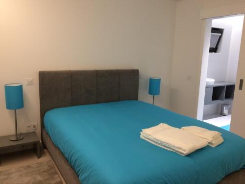 a bedroom with a bed with blue sheets and two lamps at Casa dos Valentins Geres in Geres