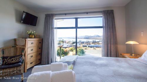 a bedroom with a bed and a large window with a view at Hillcrest Lodge B - Lake Tekapo in Lake Tekapo