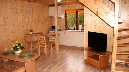 a kitchen and a living room with a television in a cabin at Domki pod gruszą in Kopalino
