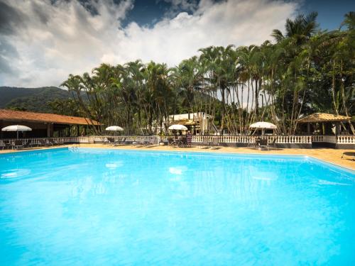 a large swimming pool with palm trees in the background at Pousada Bem Viver in Ubatuba
