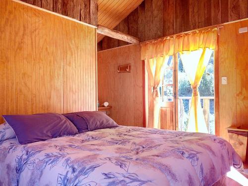 1 dormitorio con cama y ventana en Cabañas Sol de Montañas, en Futaleufú