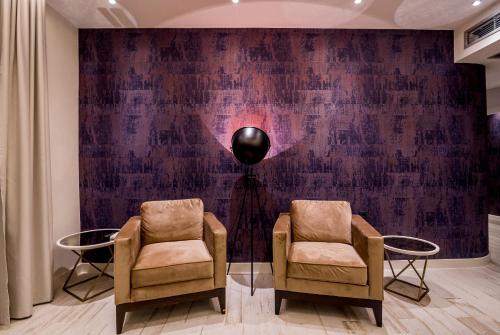 two chairs and a lamp in a room with a wall at Apartments Master 5 in Herceg-Novi
