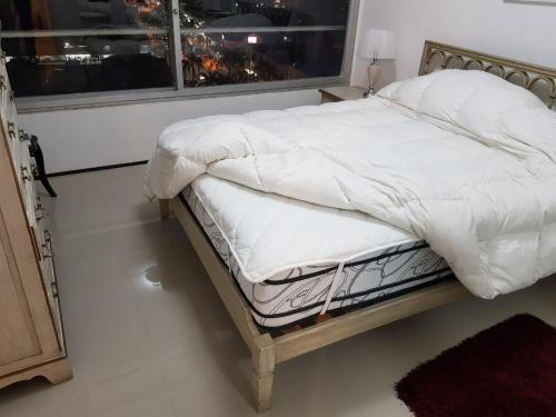 a bed with a white comforter and a window at APTO 913 - Piso 9 SANTOS DUMONT Excepcional vista al mar y a la ciudad in Punta del Este