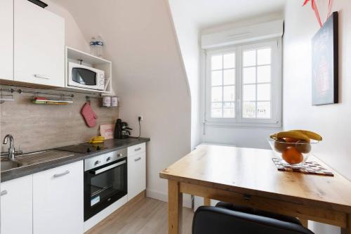 a kitchen with white cabinets and a wooden table at Cosy Solidor Beach View in Saint Malo