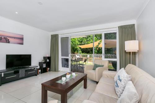 a living room with a couch and a television at Coral Coast Resort Apartment in Palm Cove