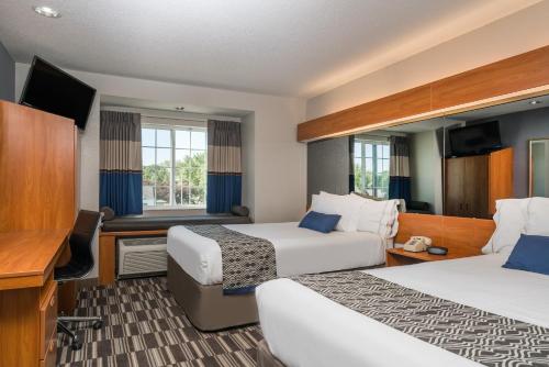 a hotel room with two beds and a desk at Microtel Inn & Suites by Wyndham Springfield in Springfield