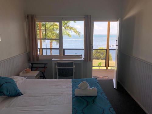 a bedroom with a bed with a view of the ocean at Squid's Ink Motel in Belmont