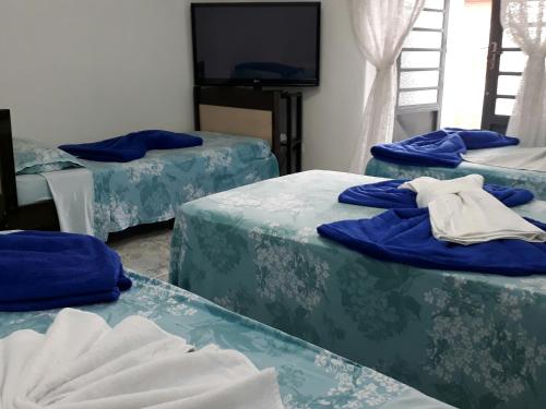 Habitación con 3 camas y sábanas azules. en Hospedaria Cambuci Unidade Ipiranga, en São Paulo