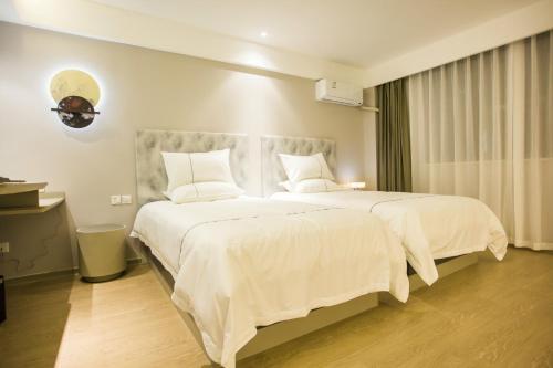 ein Schlafzimmer mit einem großen Bett mit weißer Bettwäsche und Kissen in der Unterkunft Magnotel Yangshuo West Street in Yangshuo