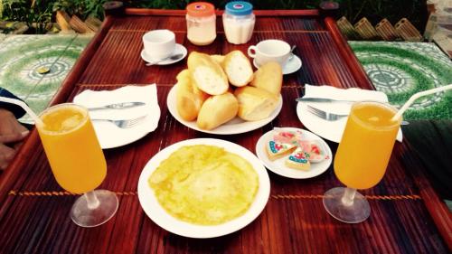een tafel met borden eten en twee glazen sinaasappelsap bij Tam Coc Thanh Dat Homestay in Ninh Binh