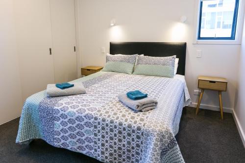 a bedroom with a bed with two towels on it at Riverwalk Apartments in Nelson