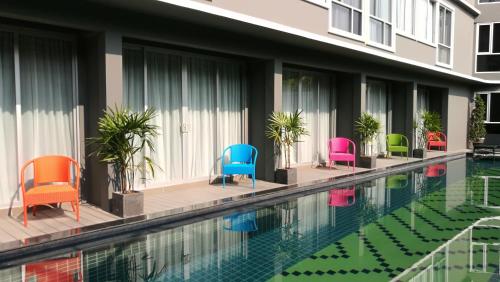 una piscina con sedie colorate accanto a un edificio di Ae Lana Chiangmai Hotel a Chiang Mai