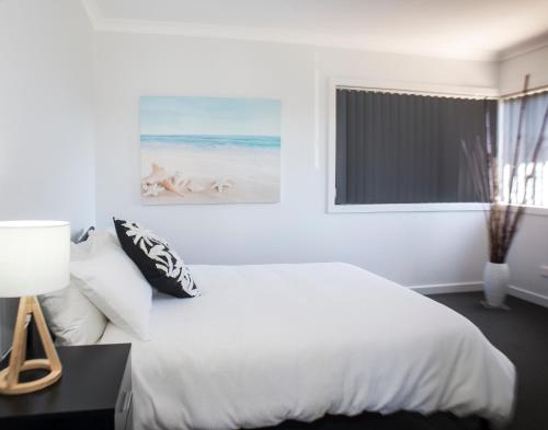 a white bedroom with a bed and a window at Bircoo Cottage Beach and Golf Getaway in Bridport