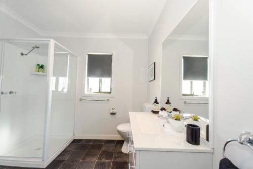a white bathroom with a shower and a toilet at Bircoo Cottage Beach and Golf Getaway in Bridport