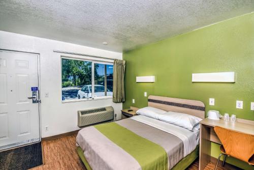 a green bedroom with a bed and a window at Motel 6-Colorado Springs, CO in Colorado Springs