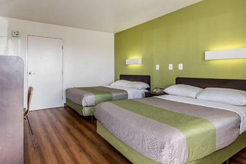 two beds in a room with green walls and wooden floors at Motel 6-El Paso, TX - East in El Paso