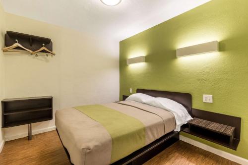 a green room with a bed and a tv at Motel 6 San Rafael in San Rafael