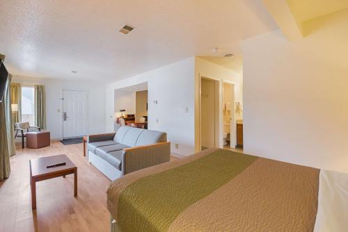 a hotel room with a bed and a couch at Studio 6 Extended Stay - Greensboro, NC in Greensboro