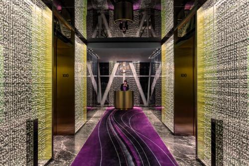 a hallway with purple and yellow walls and a chandelier at Four Seasons Hotel Guangzhou - Free Shuttle Bus to Canton Fair Complex & Overseas Buyer Registration Services during Canton Fair Period in Guangzhou