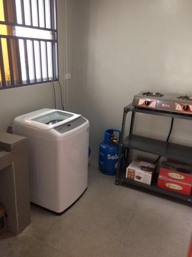 a laundry room with a washing machine and a shelf at Hillary Timog Park Homes in Angeles