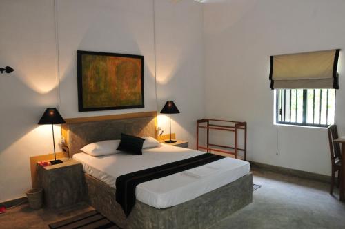 a bedroom with a bed and a painting on the wall at Waters Edge, Anuradhapura in Anuradhapura