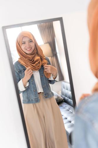 a woman wearing a hijab standing in front of a mirror at hostel DEN in Tokyo